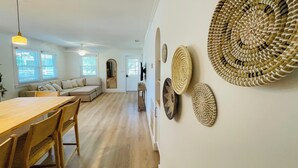 A spacious living area with a wooden dining table, chairs, a sofa, and a large mirror. - Charming Bungalow close to the beach and bay.  (Kill Devil Hills)