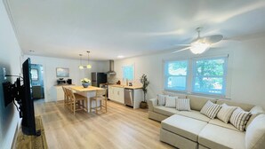 A modern kitchen with a dining area, a sofa, and a TV. - Charming Bungalow close to the beach and bay.  (Kill Devil Hills)
