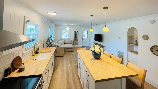 A modern kitchen with a wooden countertop, a dining area with a wooden table, and a built-in oven. - Charming Bungalow close to the beach and bay.  (Kill Devil Hills)