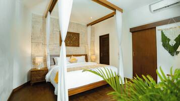 Camera da letto con letto a baldacchino, pavimento in legno, comodino con lampada e climatizzatore a parete.