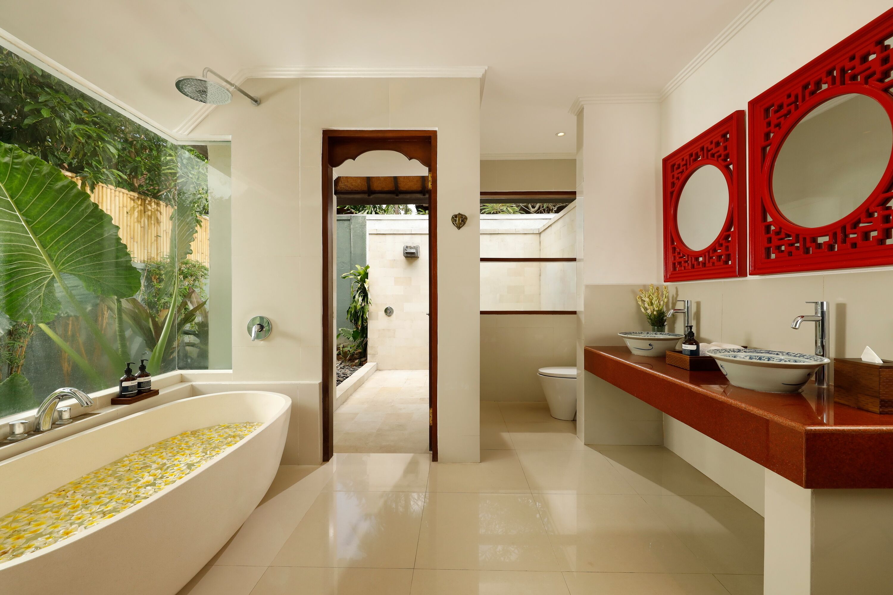 Une salle de bain moderne avec une grande baignoire, un lavabo agrémenté d’un panneau décoratif rouge et un miroir.