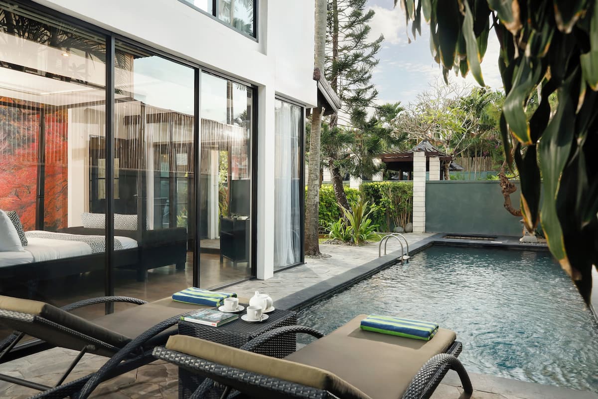 A modern outdoor pool area with lounge chairs and a glass-enclosed patio.