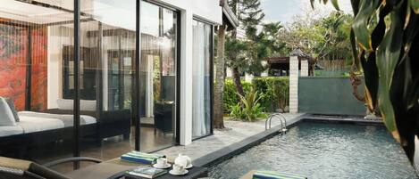 Un área de piscina moderna al aire libre con sillones de descanso y un porche con paredes de vidrio.