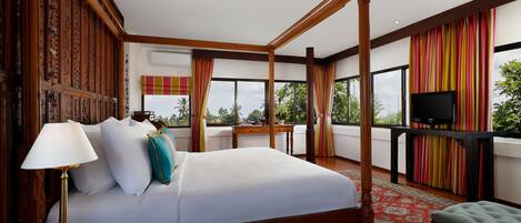 Una cama con dosel con un edredón blanco, una lámpara dorada y una almohada color turquesa.