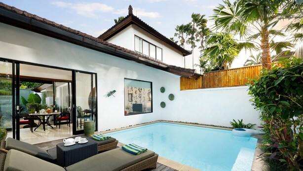 Una casa moderna amb piscina, mobiliari exterior i terrassa de fusta.