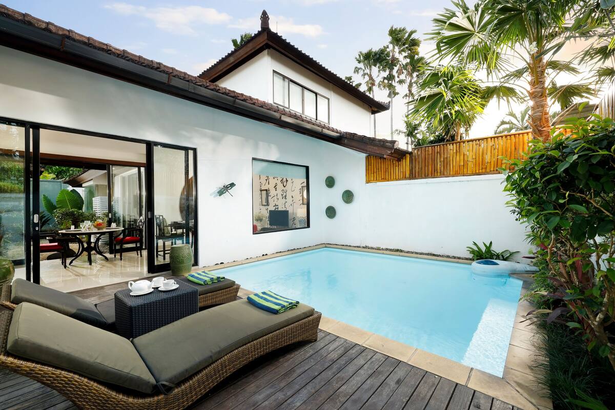 Une maison moderne dotée d’une piscine, d’un espace salon extérieur et d’une terrasse en bois.
