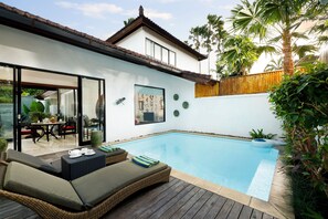 A modern house with a swimming pool, outdoor seating, and a wooden deck. - Shanti Estate Seminyak by Nakula (Seminyak)