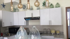 A kitchen with white cabinets, a stainless steel sink, and hanging light fixtures.