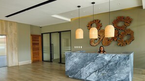 A reception desk with a marble top, wooden flooring, and pendant lights.