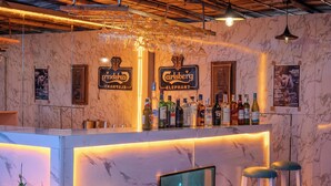 Angolo bar con parete in marmo, bicchieri appesi e insegna luminosa con scritto "Avenue".