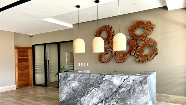 Una moderna zona de recepción con mostrador de mármol, luces colgantes y decoración mural.
