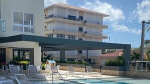 Una piscina con sillas de descanso y un edificio al fondo.