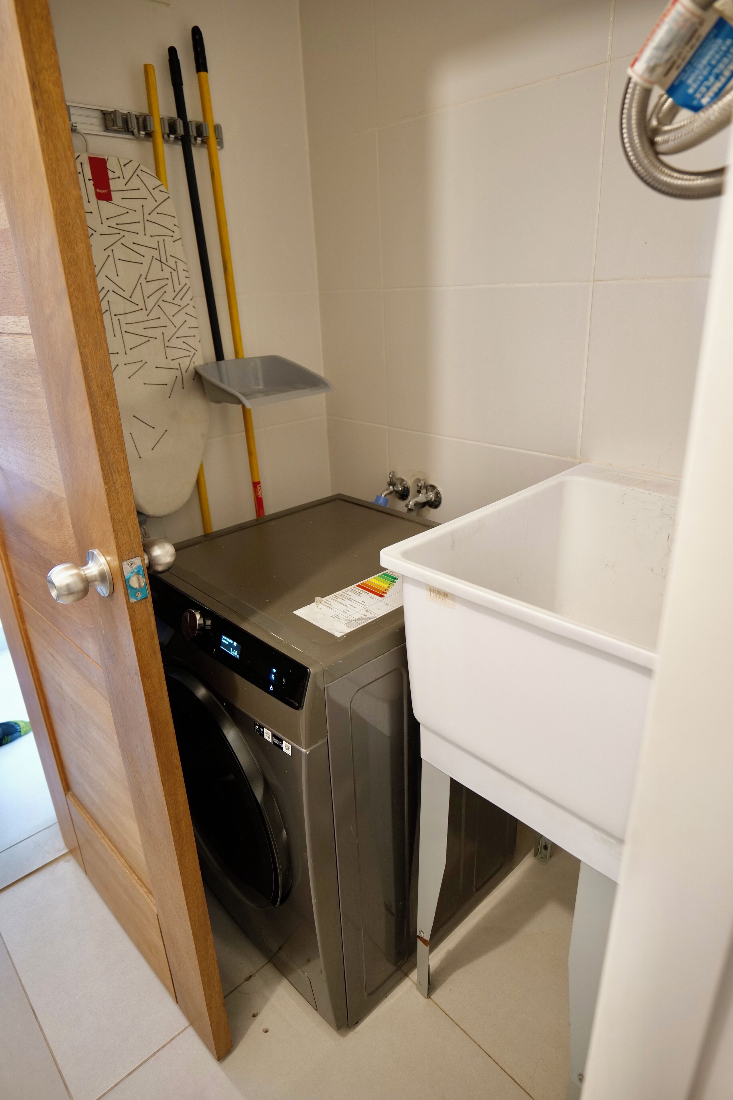 Een wasruimte met een wasmachine, een droogrek en een witte wasbak.