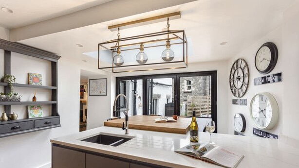 A modern kitchen with a central island, a built-in sink, and a hanging light fixture. - The Coronation Family Cottage | Ridgestone (Lindale)
