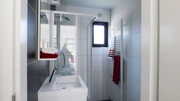 A modern bathroom with a white sink, mirror, and towel rack.