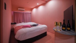 A bedroom with a bed, pink curtains, and two wine bottles on a shelf. - HOTEL elLle - Adults Only (Toyama)