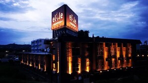 A hotel with a prominent illuminated sign, a modern architectural design, and a series of lights along the building's facade. - HOTEL elLle - Adults Only (Toyama)