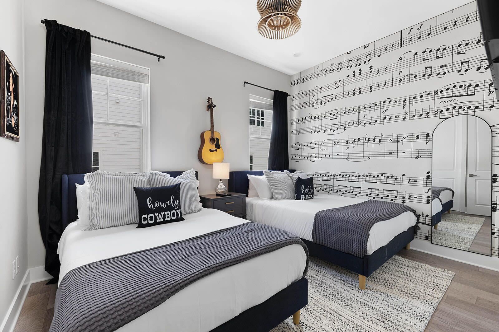 A bedroom with two beds, a guitar, and a wall with musical notes.