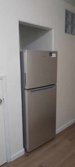 Modern kitchenette with refrigerator, telephone, and cabinetry.