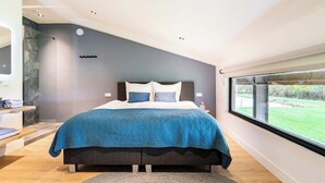 A modern bedroom with a large bed, a view of the outdoors, and a built-in bench with a towel. - Luxury Farmstay – Sleep in Style Among the Cows (Loenen aan de Vecht)