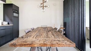 A modern kitchen with a large wooden dining table, a black refrigerator, and a hanging light fixture. - Luxury Farmstay – Sleep in Style Among the Cows (Loenen aan de Vecht)