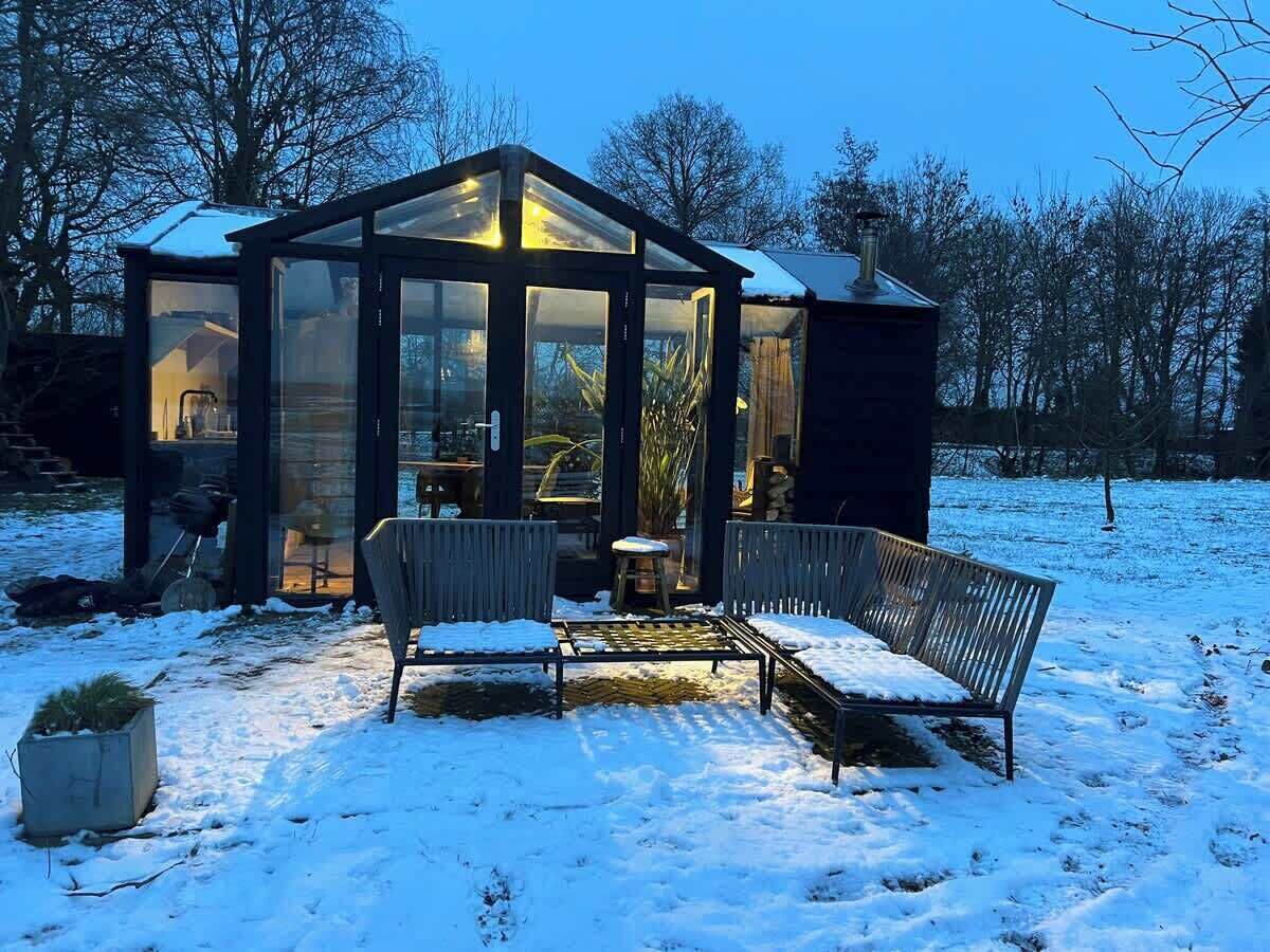 Una gruta de cristal con un banco y una mesa, rodeada de nieve.