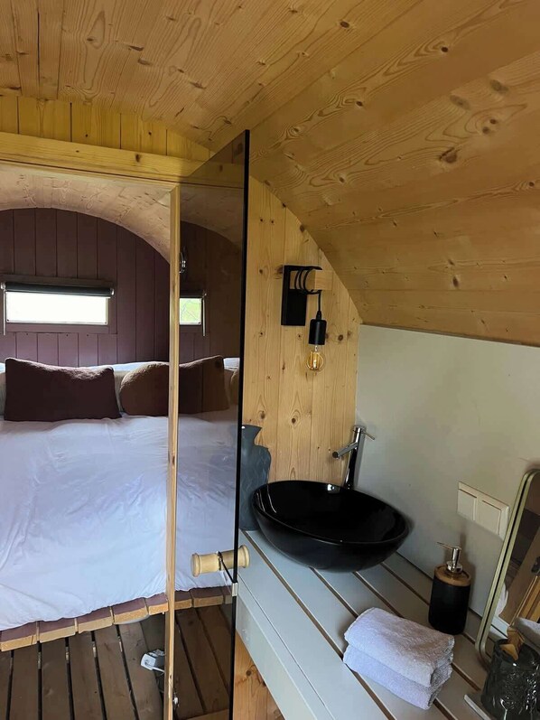 A bedroom with a bed, a window, a sink, and a mirror.