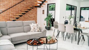 A modern living room with a grey sofa, a coffee table, and a staircase with wooden steps.