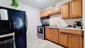 Une cuisine avec des meubles de rangement en bois, un réfrigérateur noir, un four à micro-ondes, une cuisinière et un évier.
