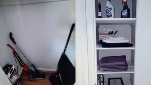Un espace de rangement contenant des produits de nettoyage, un balai et un aspirateur.