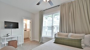 Una habitación de hotel moderna con cama, televisor, escritorio y ventana con cortinas.