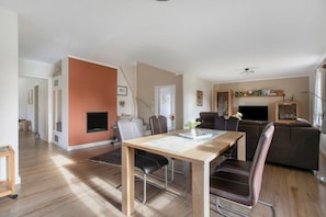 A modern living room with a dining area, a fireplace, and a television.