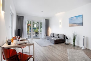 A modern living room with a sofa, dining table, and a view of the outdoors.