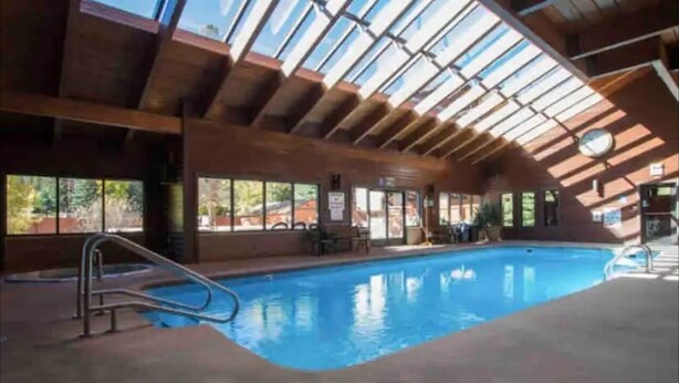 An indoor swimming pool with a glass ceiling, metal railings, and a clear view of the outdoors. - Amazing Views, hot tubs, pool, sauna and plenty of parking at cozy Frisco condo (Frisco)