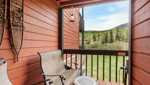 A wooden deck with a bench and a small table, overlooking a grassy area with trees. - Amazing Views, hot tubs, pool, sauna and plenty of parking at cozy Frisco condo (Frisco)