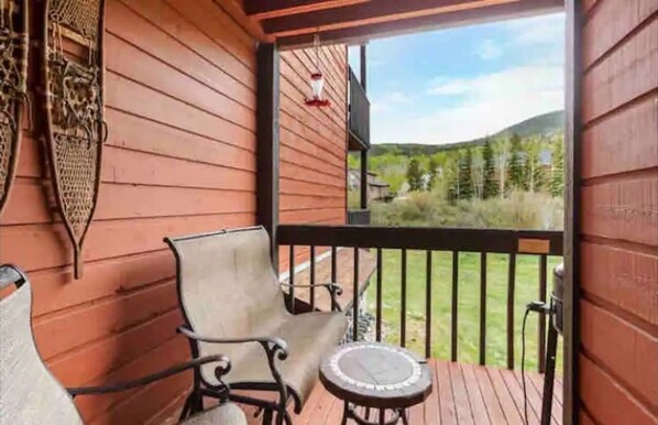 A wooden deck with a bench and a small table, overlooking a grassy area with trees. - Amazing Views, hot tubs, pool, sauna and plenty of parking at cozy Frisco condo (Frisco)