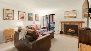 A living room with a fireplace, a sofa, a small table, and framed pictures on the wall. - Amazing Views, hot tubs, pool, sauna and plenty of parking at cozy Frisco condo (Frisco)