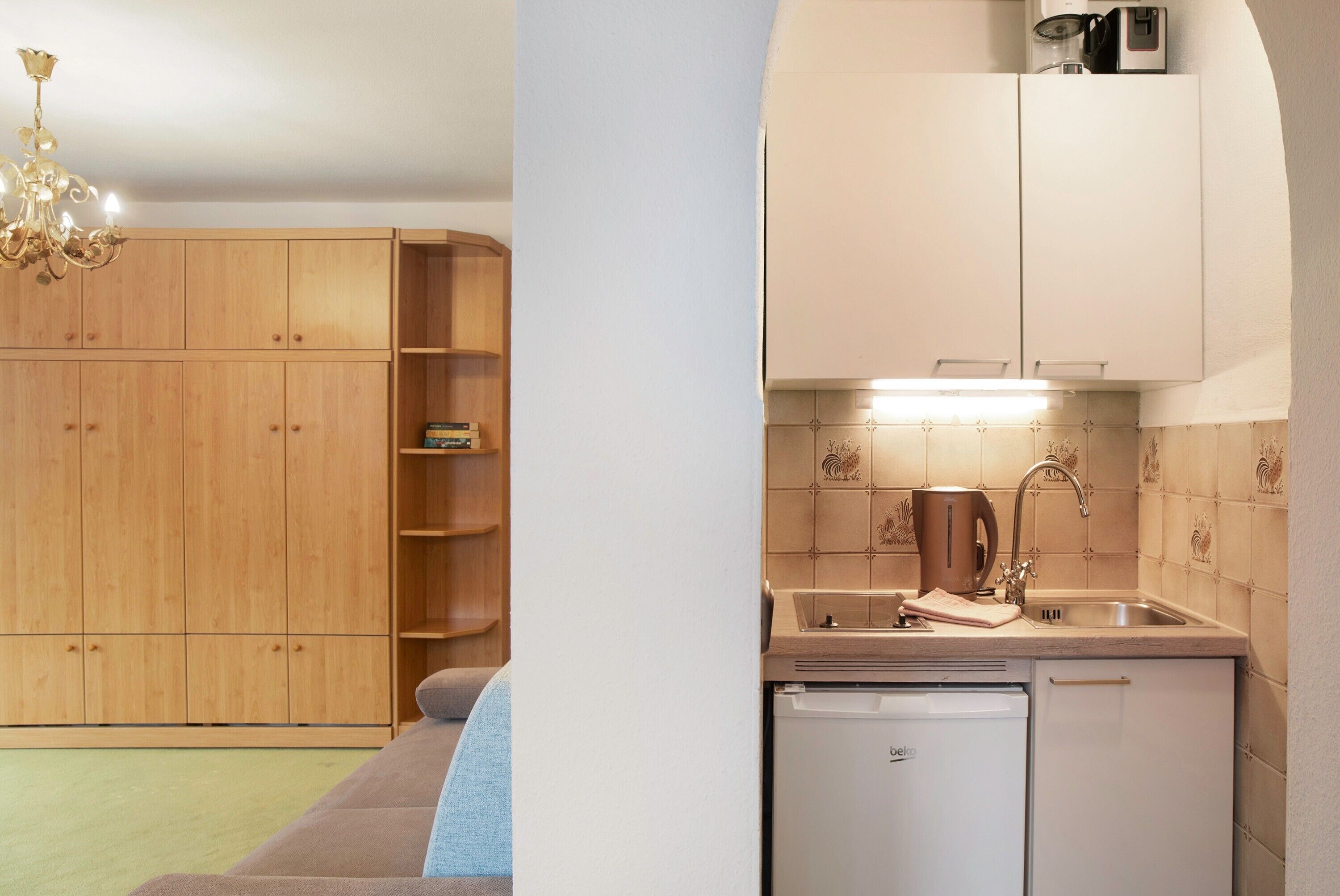 Una cocina compacta con lavavajillas incorporado, un lavabo y cafetera.