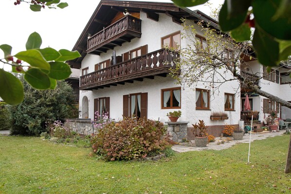 Ein zweistöckiges Gebäude mit Balkon, Pflanzkübeln und einer Steinmauer.