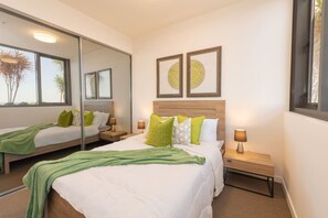A hotel room with a large bed, bedside tables, a mirror, and framed artwork on the wall.