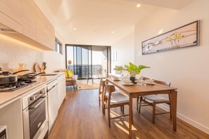 A modern kitchen with a dining area, a view through a glass door, and a dining table set for four.
