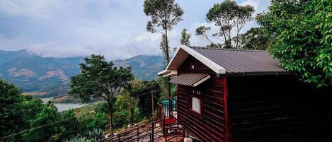 A small cabin with a metal staircase and a view of a lake and mountains.