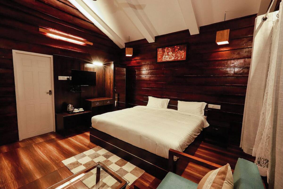 A bedroom with a large bed, wooden walls, a television, and a checkered rug.