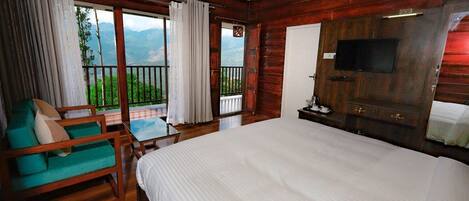 Una habitación de madera con una cama grande, un televisor montado en la pared y un balcón con vistas a las montañas.