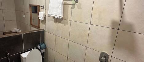 A bathroom with a toilet, a towel rack, a hand dryer, and a showerhead.