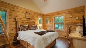 Un dormitori de cabana de fusta amb un llit, un taulell i una escala.