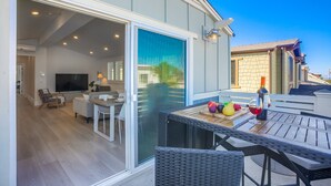 Un intérieur moderne avec un coin repas, un téléviseur et une grande porte-fenêtre coulissante donnant sur une terrasse extérieure.