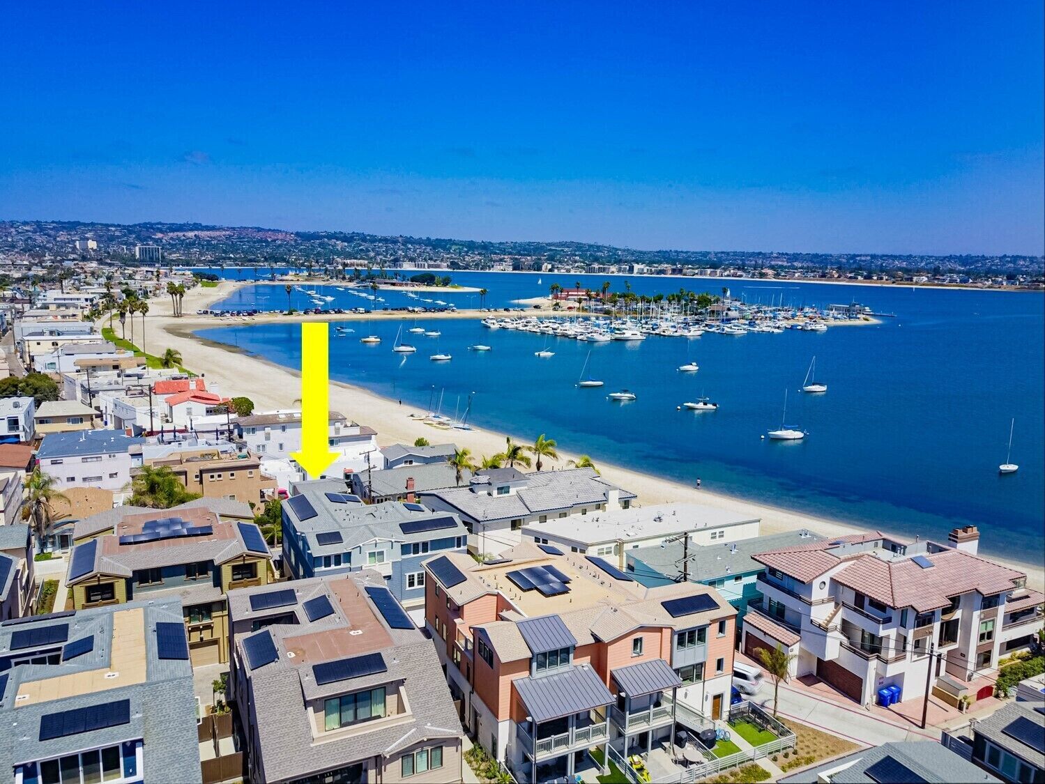 Zona residencial costera con casas modernas, un puerto deportivo y una playa.
