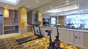 A gym with treadmills and an elliptical machine, a patterned carpet, and a large mirror reflecting the room. - Wassim Hotel Fushun Yantan (Zigong)