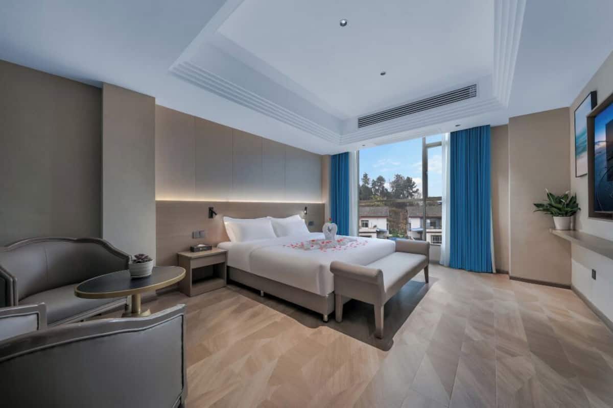Une chambre d’hôtel moderne dotée d’un grand lit, d’un coin salon avec une petite table et offrant une vue sur l’extérieur.
